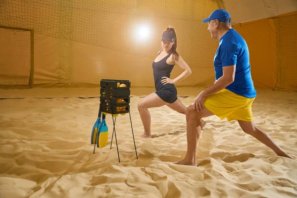 Perplexed Female Sportswear Doing Leg Lunges Sand While Nearby Man — Stockfoto