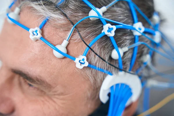 Middle-aged man on the diagnosis of EEG - electroencephalography, a cap of sensors on his head