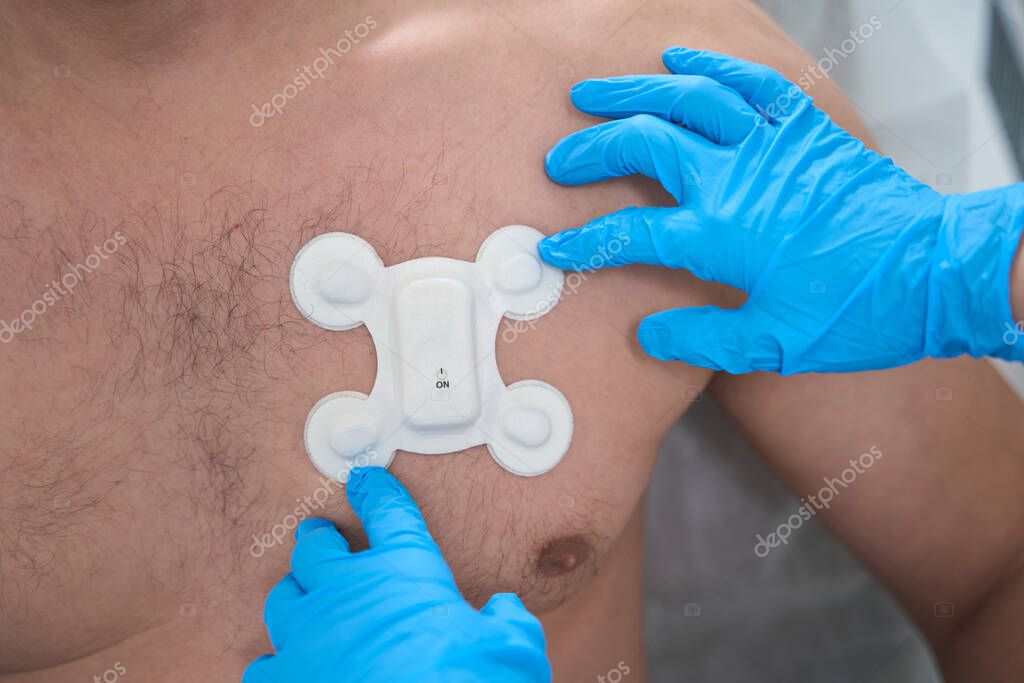 Doctor Glues The Electrode To The Chest Of A Man With A Naked Torso For Diagnostic Ecg