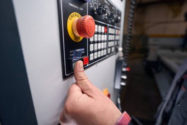 Male in standing in workshop near equipment, selecting command on control panel