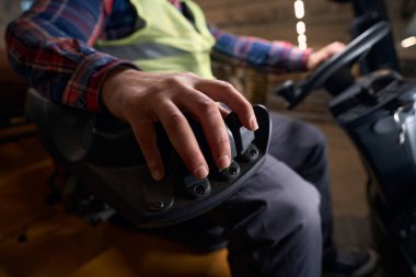 Worker in protective clothes sitting in the loading machine and driving in workhouse