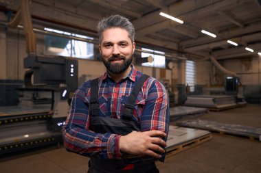 Portrait of smiling male in protective clothes standing in workshop, looking at the camera