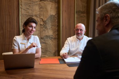 Doctors and client in a business suit are sitting at a desk and talking, they are discussing a treatment plan