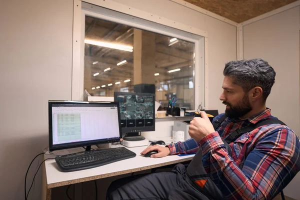 Security guard working in video surveillance room, drinking tea, looking at computer