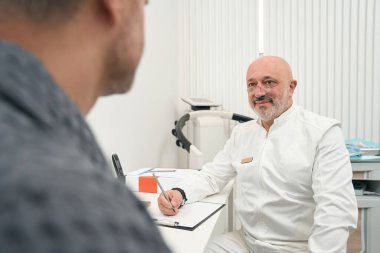 Close up portrait of handsome seriously male doctor is listening his patient in the medical office