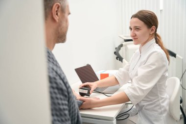 Close up side view portrait of beautiful Caucasian female doctor is holding oligoscan in hand during the examining patient health indicator in the office