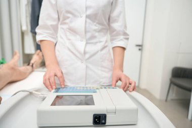 Cropped head portrait of doctor is using electronic devices for examining heartbeat of patient in the hospital