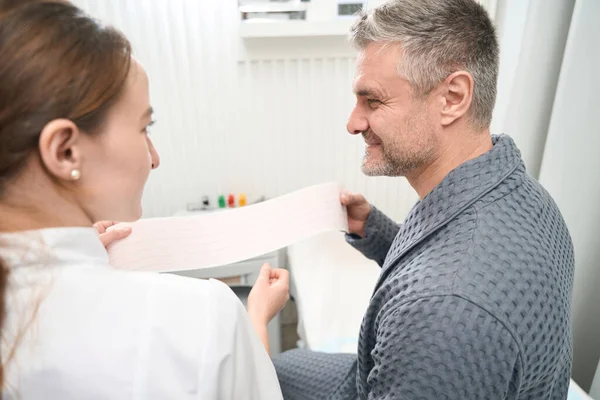 Waist up back view portrait of handsome smiling man is talking with doctor cardiologist in medicine center