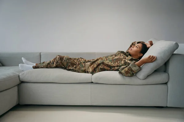 Задумчивая Военная Женщина Отдыхает Яркой Гостиной Мягком Диване Военной Одежде — стоковое фото