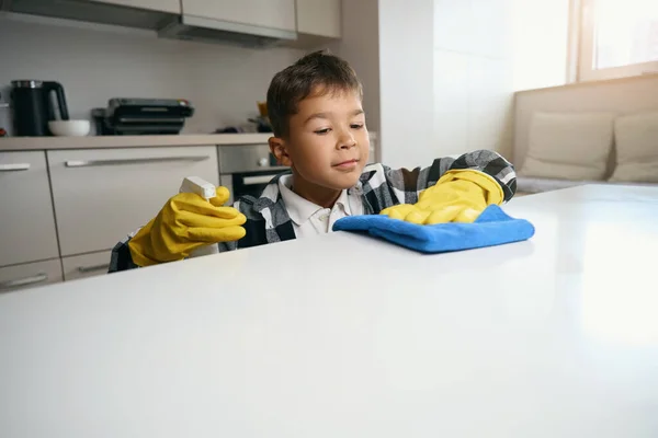 身穿格子呢衬衫 戴防护手套的年轻人帮着打扫房子 他洗了厨房的表面 — 图库照片