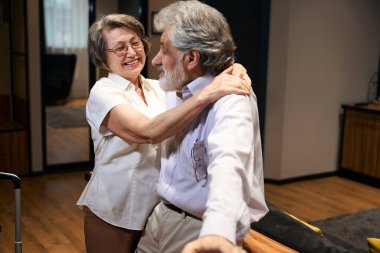 Old lady and man entered rented hotel room, looking at each other, embrace and talking