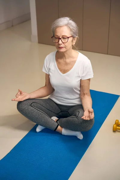 Yoga Training Elderly Woman Meditates Lotus Position Dumbbells Lie Nearby — стоковое фото