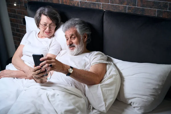 Elderly Female Male Lying Bed Bedroom Male Holding Mobile Phone — Stockfoto