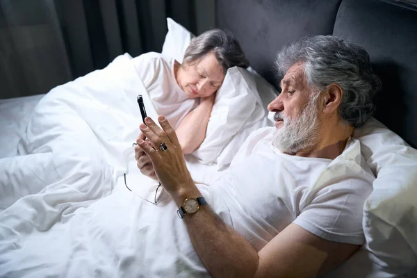 Elderly Female Male Lying Bed Bedroom Male Holding Mobile Phone — Fotografie, imagine de stoc