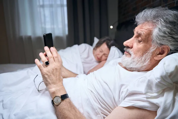 Літня Жінка Чоловік Лежать Ліжку Спальні Чоловік Тримає Мобільний Телефон — стокове фото