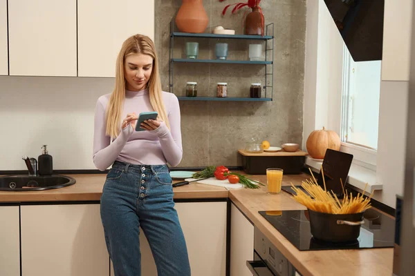 Спокійна Зосереджена Жінка Спирається Кухонний Стіл Дивиться Екран Смартфона — стокове фото