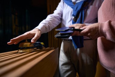 Gündelik elbiseli bir adam kayıt için otel personelini arıyor. Yanında pasaportu olan bir arkadaşı var.
