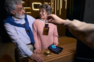 İyimser büyükanne ve büyükbaba, pasaport sahibinin resepsiyondaki otel odasının anahtarlarını alıyorlar.