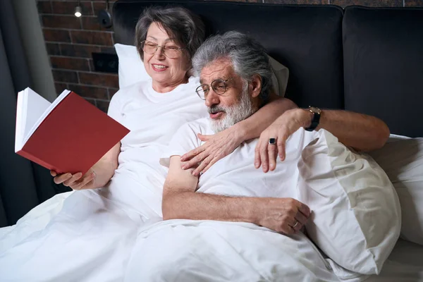 Äldre Kvinna Och Man Liggande Sängen Sovrummet Hustru Läser Bok — Stockfoto