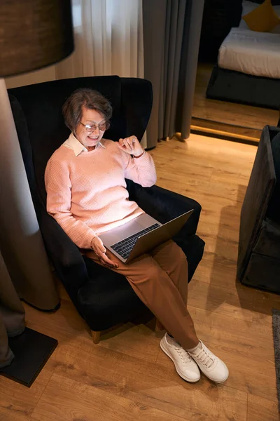 Elderly Woman Glasses Sits Laptops Comfortable Chair Communicates Online Her — Stock Photo, Image