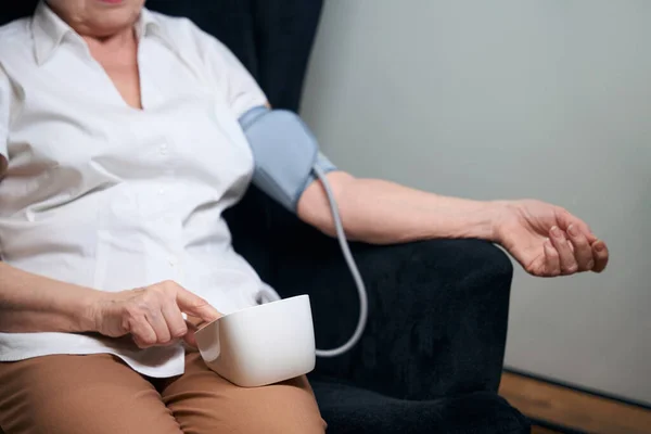孤独な老婦人は椅子に座って 自動血圧計で彼女の血圧を測定します — ストック写真