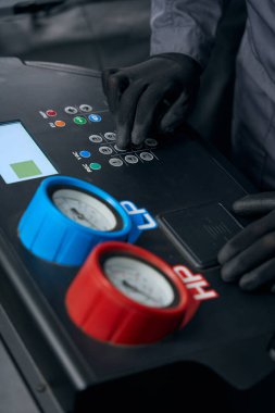 Kompresörün yanındaki koruyucu elbiseli tamirci ve lastik montajında araba kliması.