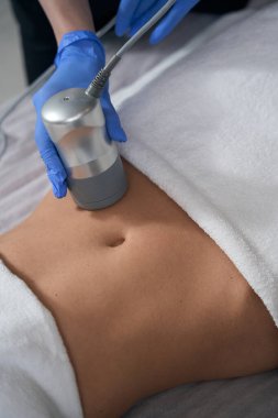 Kuaförde kanepede uzanmış, koruyucu eldivenli kozmetik uzmanı karın röntgeni çekiyor.