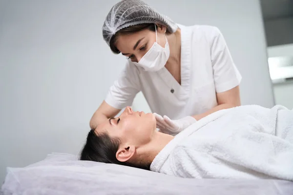 Mulher Bonita Deitada Sofá Cosmetologista Luvas Proteção Máscara Fazendo Massagem — Fotografia de Stock