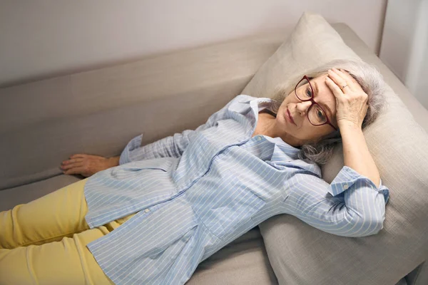 Tired Elderly Woman Lies Sofa Holds Her Head She Unwell — Stock Photo, Image