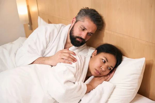 Serious Young Male Lying Bed While Touching Shoulder His Sad — Stock Photo, Image
