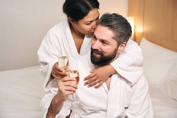 Vrolijke Vrouw Met Glas Champagne Knuffelen Zoenen Gelukkig Vriendje Bed — Stockfoto