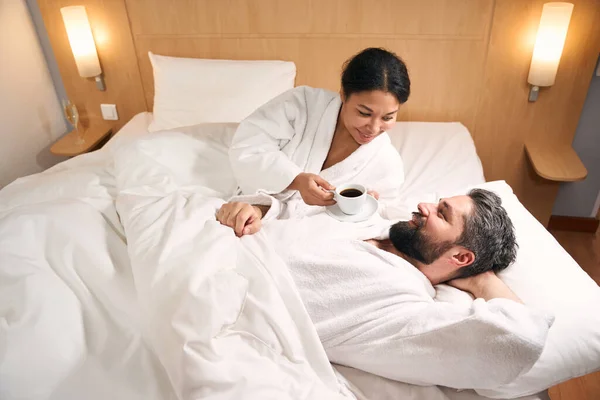 Vrolijke Vrouw Met Kopje Koffie Schotel Liggend Bed Naast Gelukkig — Stockfoto