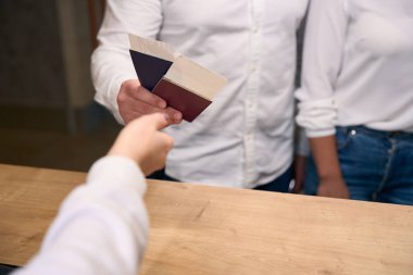 Turist çiftin seyahat belgelerini resepsiyondaki resepsiyoniste verirken çekilmiş bir fotoğrafı.