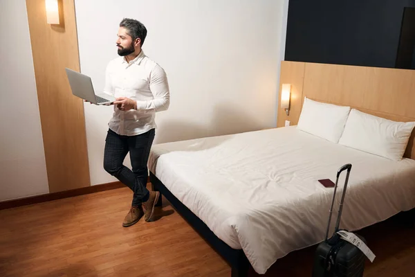 认真专注的优雅男性创业者 手握笔记本电脑 站在酒店房间里 — 图库照片