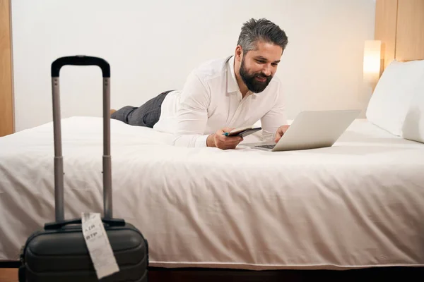 Smiling Contented Man Lying Bed His Luxury Suite While Typing — Stock Photo, Image
