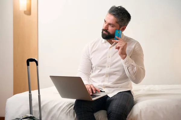 Tankeväckande Gentleman Med Betalkort Och Bärbar Dator Sittande Sängen Hotellrum — Stockfoto