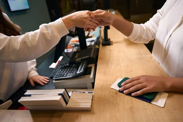 Cropped photo of front desk clerk shaking hands with female guest upon arrival