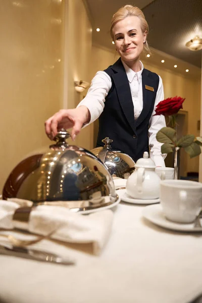 Hotel waitress on a trolley delivered hot food to the hotel room, woman in uniform
