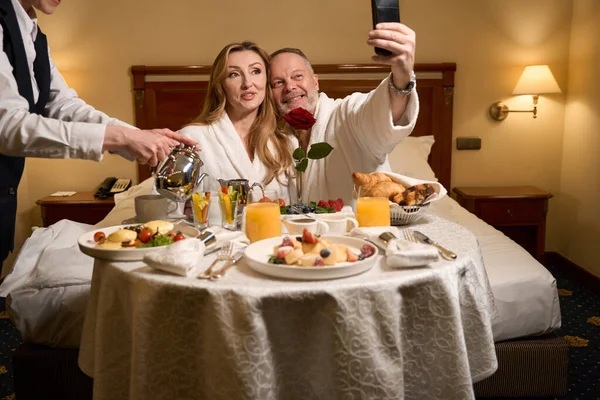 Married Couple Celebrating Wedding Anniversary Taking Selfie Waitress Serves Them — Stock Photo, Image
