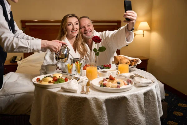 豪華なホテルで結婚記念日を祝う大人のカップル ウェイターは彼らのためにロマンチックな食事を設定します — ストック写真