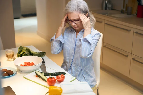 Oudere Grijs Harige Vrouw Heeft Hoofdpijn Zit Aan Keukentafel — Stockfoto