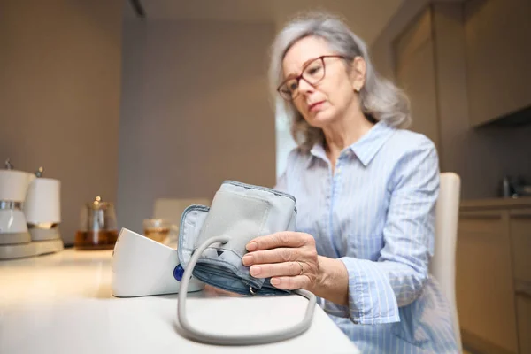 Elderly Tired Woman Uses Tonometer Monitor Blood Pressure She Sits — Stock Photo, Image
