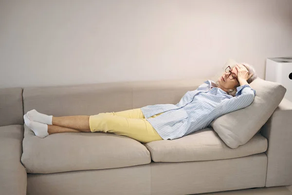 Dünne Großmutter Legt Sich Auf Das Sofa Sie Hat Kopfschmerzen — Stockfoto