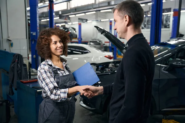 中年男性と若い女性の自動車修理工の間の握手 彼らは車の修理店で通信します — ストック写真