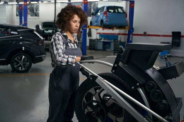 汽车修理厂现代设备上与汽车车轮打交道的多种族妇女 戴防护手套的维修妇女 — 图库照片