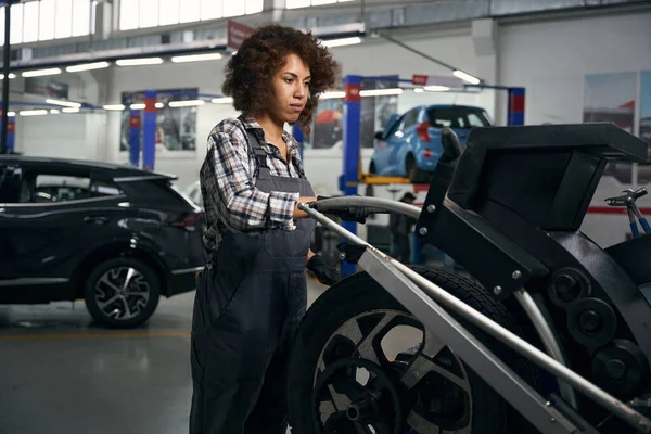 集中多种族妇女穿着工作服 与车轮一起在汽车修理店工作 戴着防护手套的修理工 — 图库照片