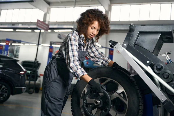 かなり多人種間の女性とともに巻き毛チェックホイールで車の修理店 作業服の修理女性 — ストック写真