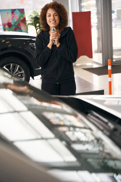 幸せな車のディーラークライアント彼女の手の中に新しい車への鍵を保持し 快適なカジュアル服の女性 — ストック写真
