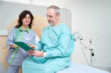 Erkek hasta, laboratuvarda tomografi çekmeden önce anket imzalıyor.