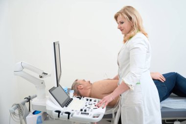 Kadın doktor, teşhis için ekokardiyogramla erkek hastanın kalbini inceliyor. Tıbbi muayene, ultrason. Tıbbi ekipman
